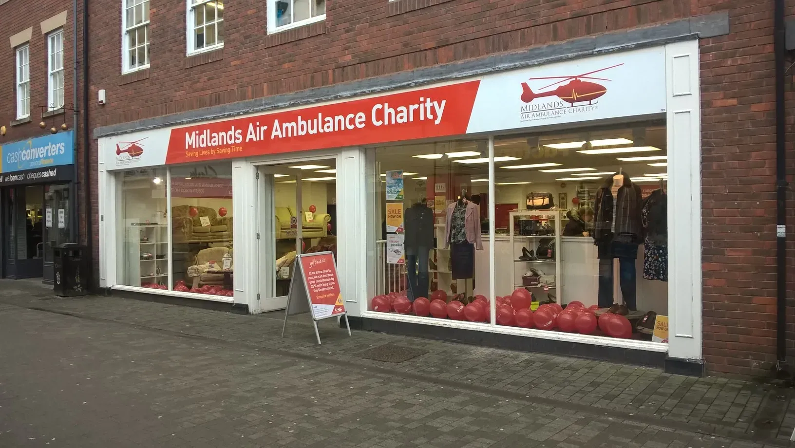 The front of Midlands Air Ambulance charity shop in Wellington, Telford with bright red signage.