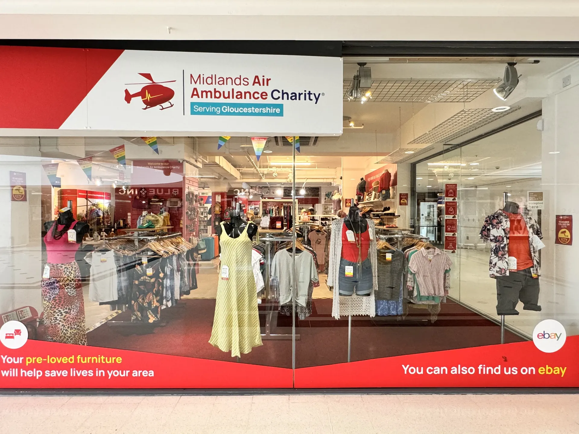 The front window display of Midlands Air Ambulance Charity shop in Gloucester, with a bright yellow dress in the window.