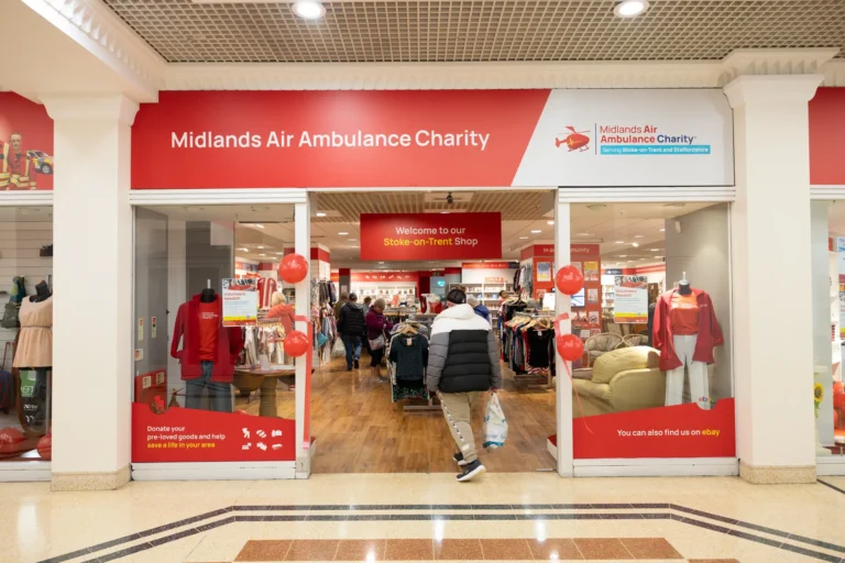 The front window display of Midlands Air Ambulance Charity Shop in Stoke-On-Trent, with a male in a black jacket walking into the store.