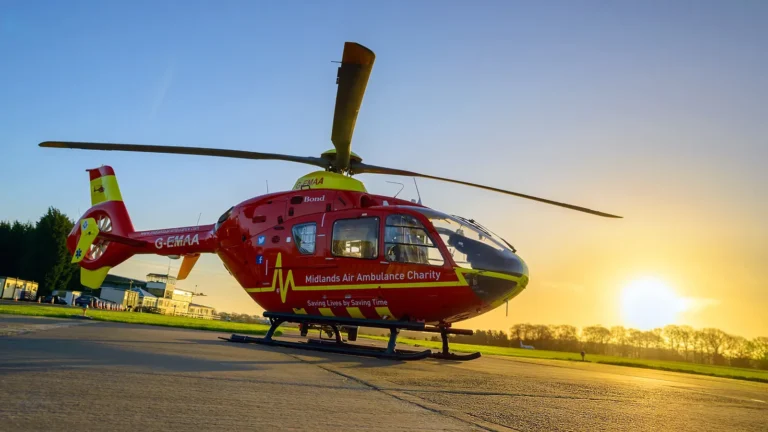 Maac Helicopter Sitting On The Tarmac At Sunset With Sun Setting