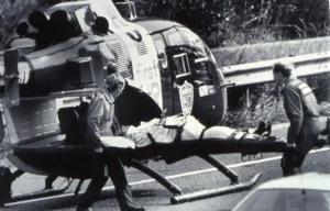 Maac Man Being Carried By A Man On A Stretcher