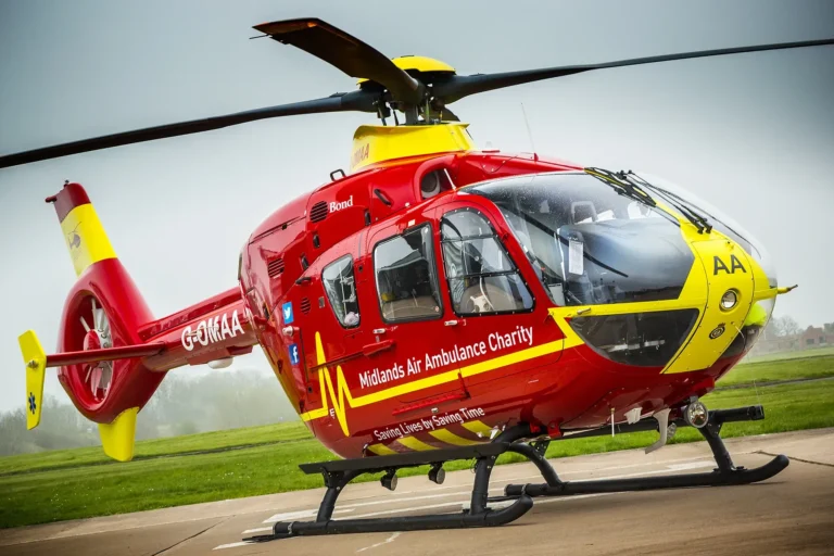Maac Red Helicopter With Yellow Trim Sitting On A Runway