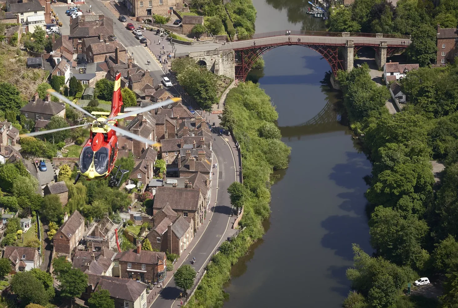 A Midlands Air Ambulance helicopter flying over Shropshire, with a river in the aerial view.