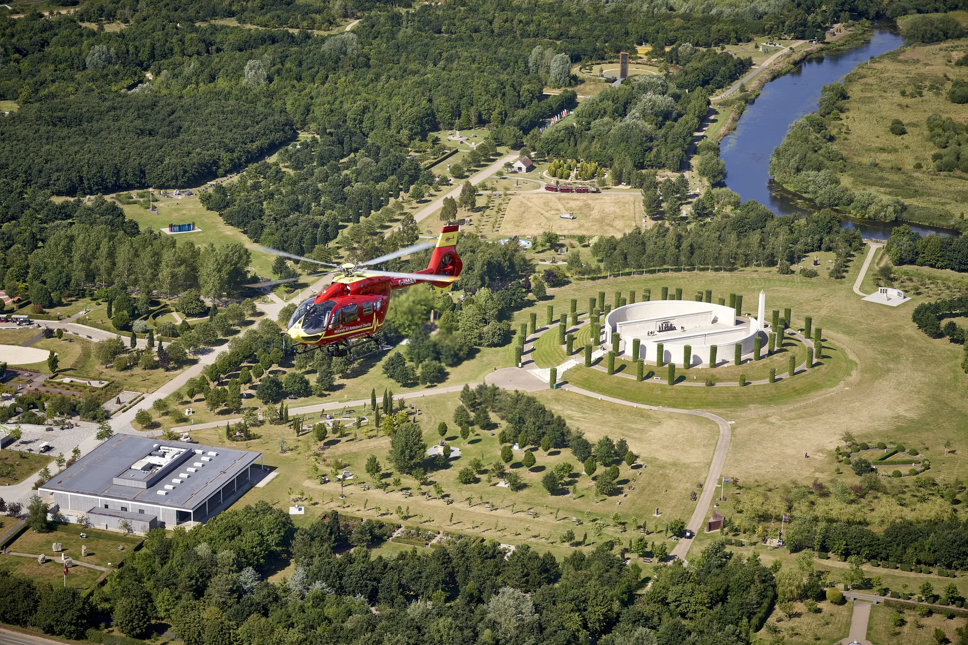 A Midlands Air Ambulance helicopter flying over Staffordshire countryside, with a river in view.