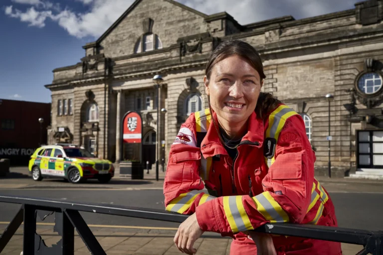 Maac Staffordshire Woman In Red Jacket Standing In Front Of A Building With A Police Car In The Background