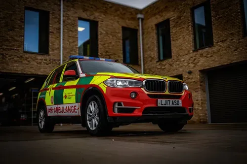Maac A Close Up Of A Red And Yellow Bmw Suv Parked In Front Of A Building