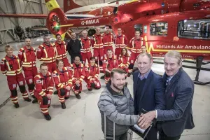 Maac Crew Of Men In Red Uniforms Standing In Front Of A Helicopter