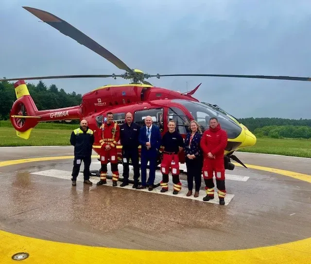 Maac Crew Of Men Standing In Front Of A Helicopter On A Runway