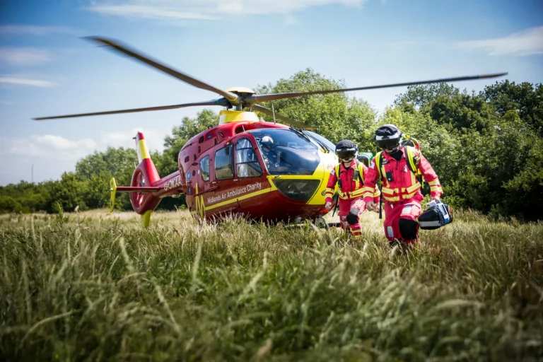 Maac Firefighters Walking Towards A Helicopter In A Field With Trees In The Background
