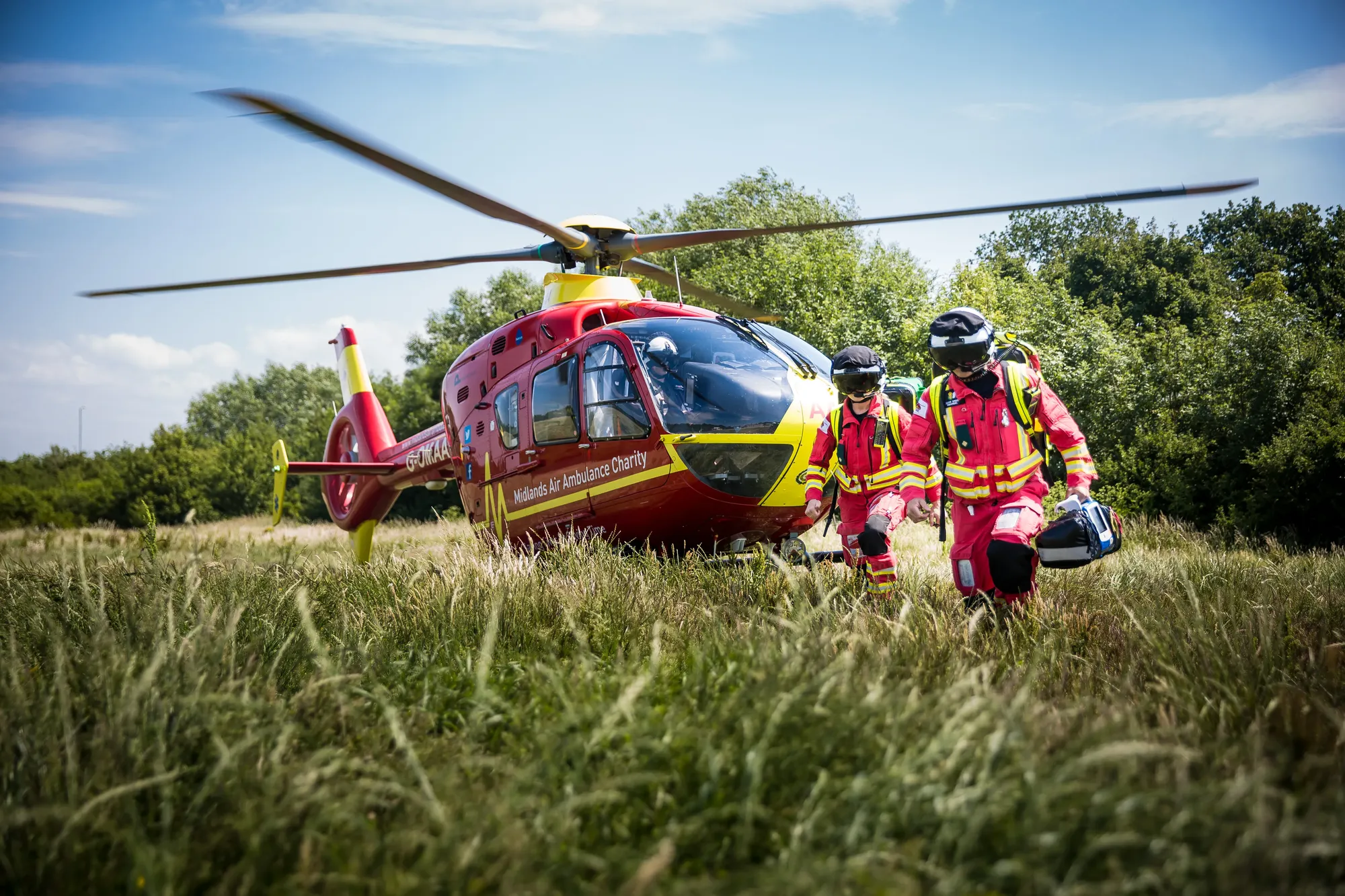 Maac Firefighters Walking Towards A Helicopter In A Field With Trees In The Background