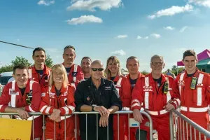 Maac Group Of People In Red Uniforms Standing Behind A Fence