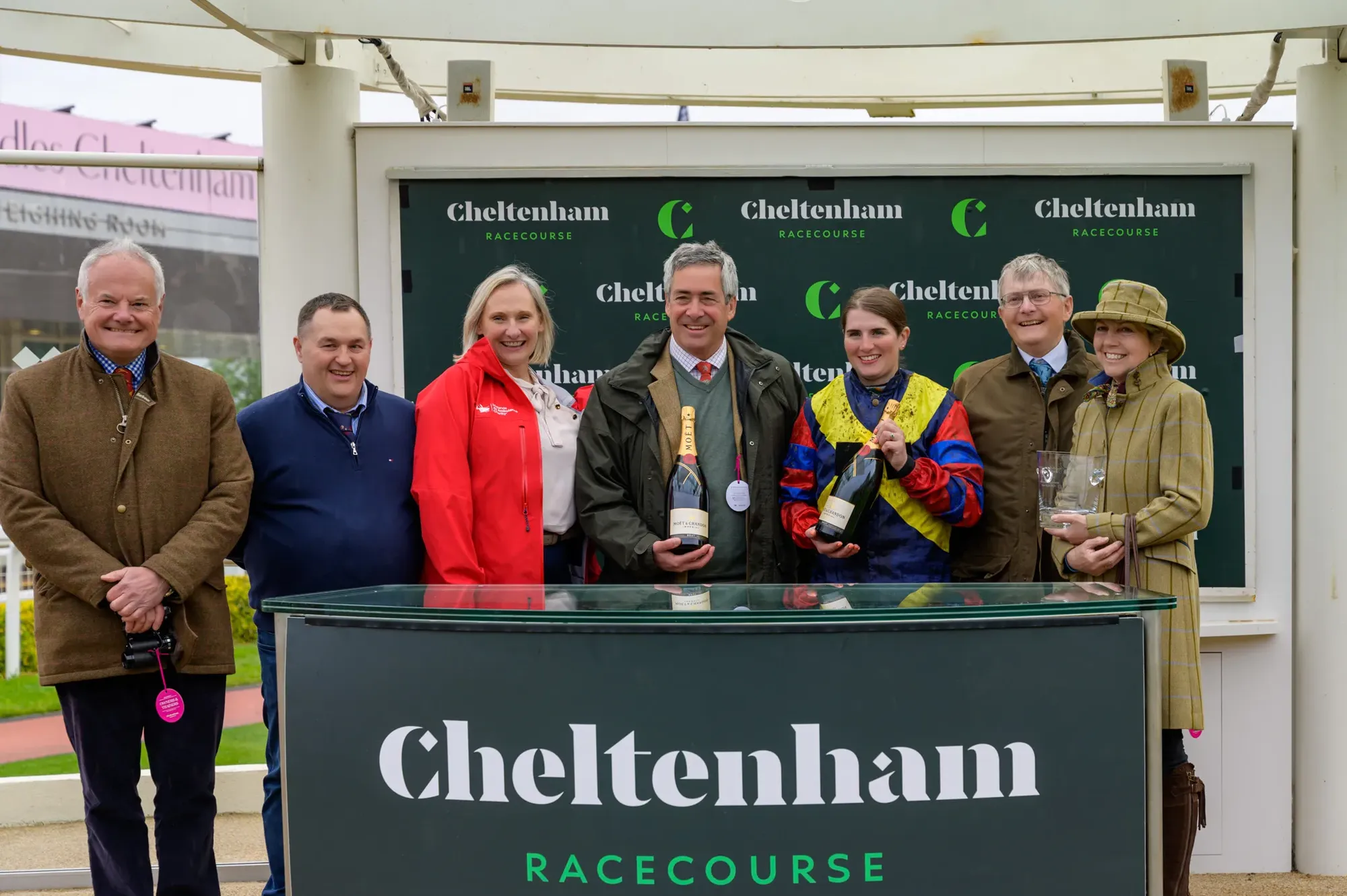 Maac Group Of People Standing Behind A Table With A Bottle Of Wine