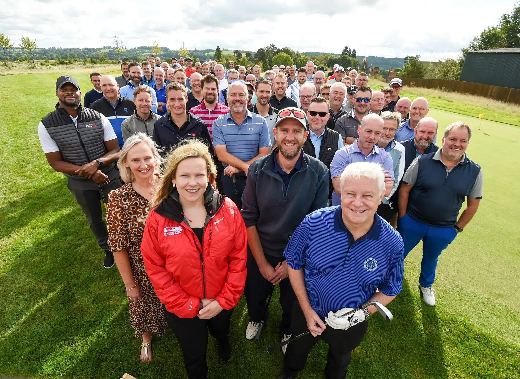 Maac Group Of People Standing In A Field With A Golf Ball