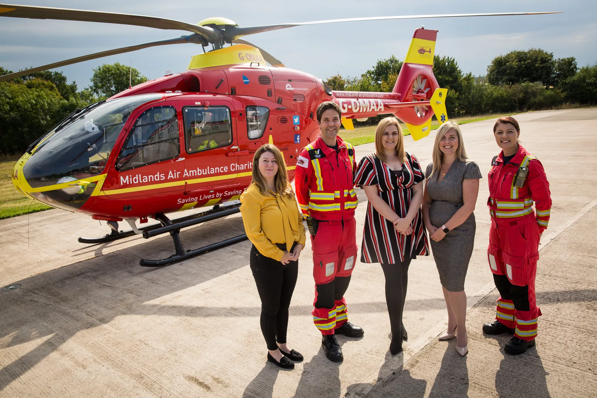 Maac Group Of People Standing In Front Of A Helicopter