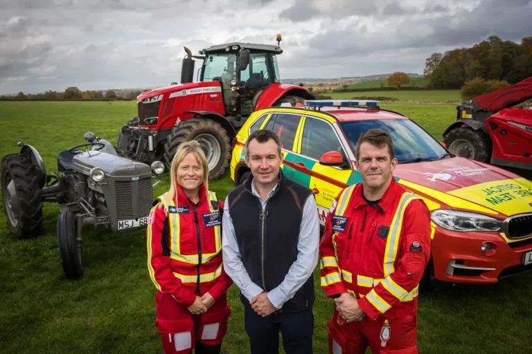 Maac Group Of People Standing In Front Of A Tractor And A Car