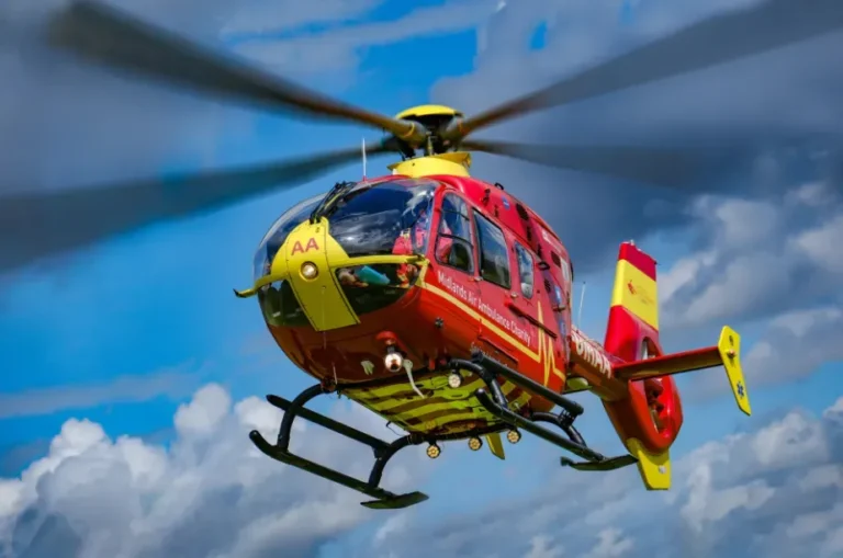 Maac Helicopter Flying In The Sky With A Red And Yellow Helicopter