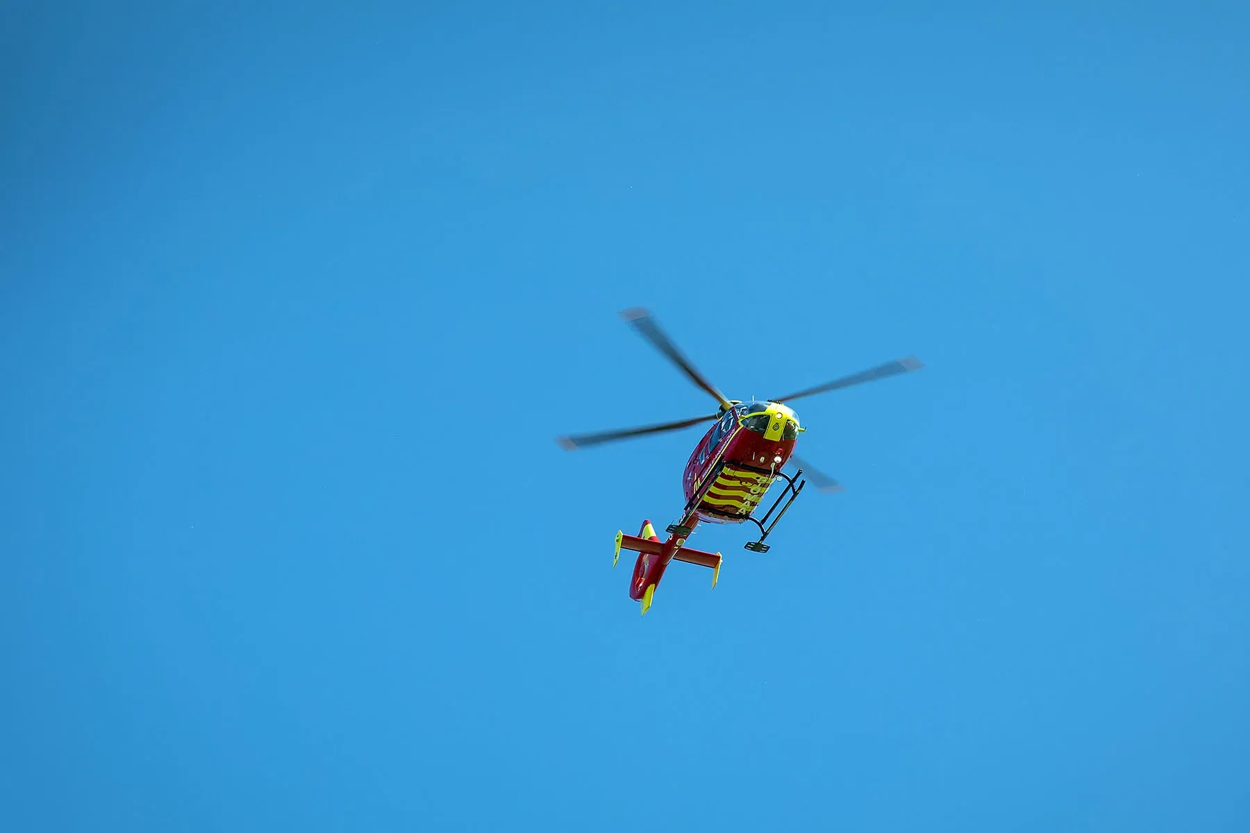 Maac Helicopter Flying In The Sky With A Red And Yellow Helicopter