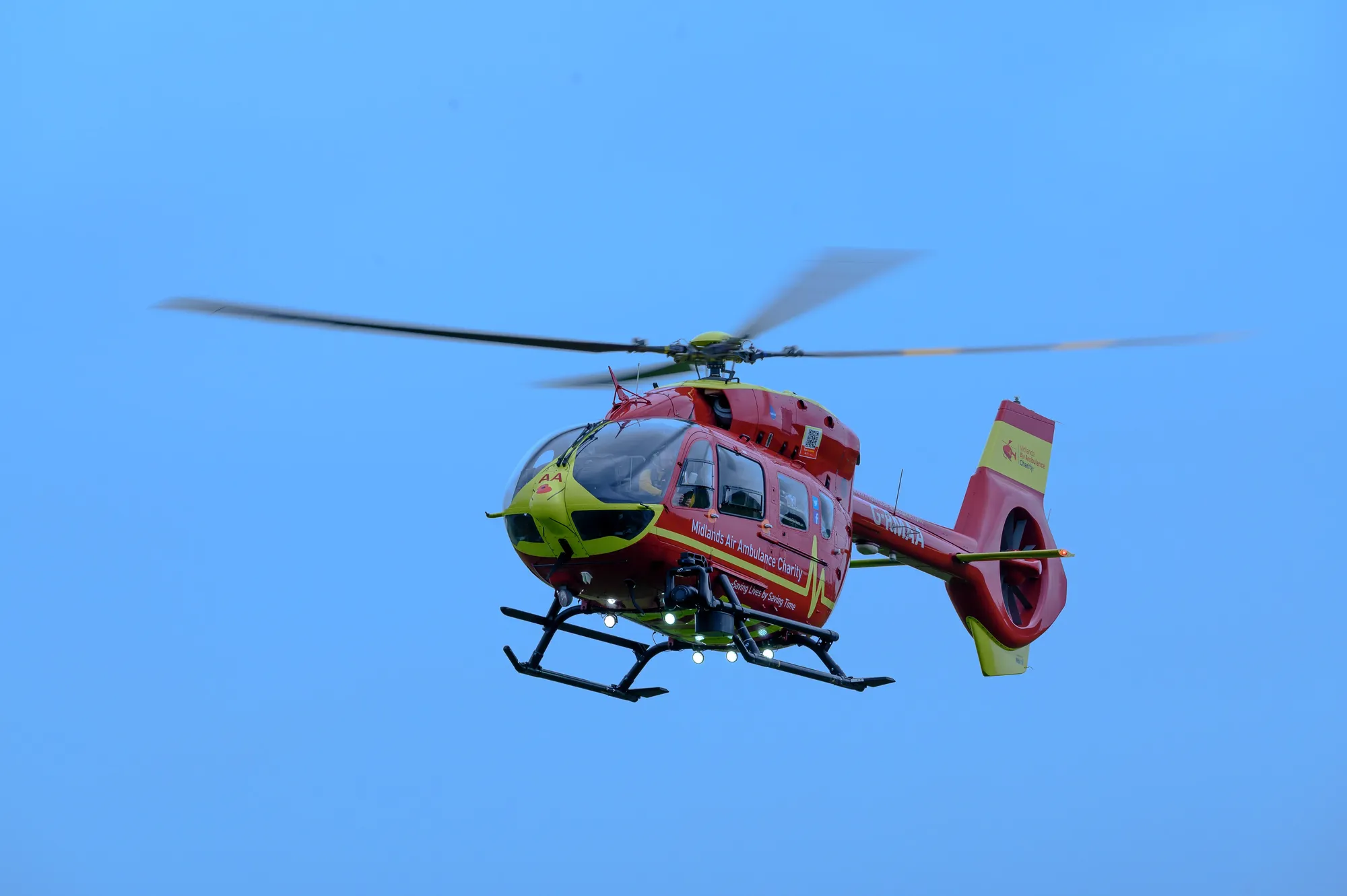 Maac Helicopter Flying In The Sky With A Red And Yellow Tail
