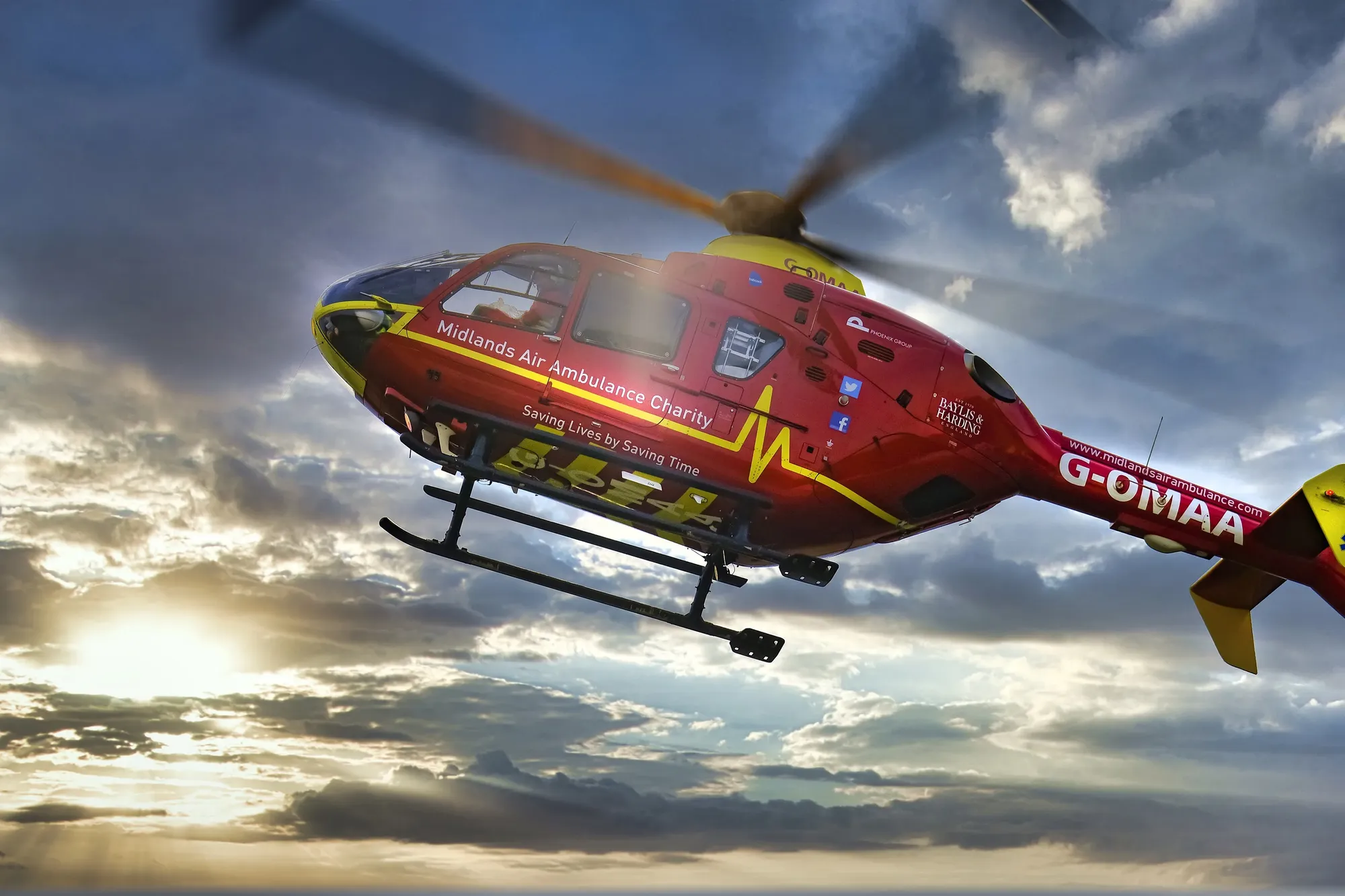 Maac Helicopter Flying In The Sky With A Sun Behind It