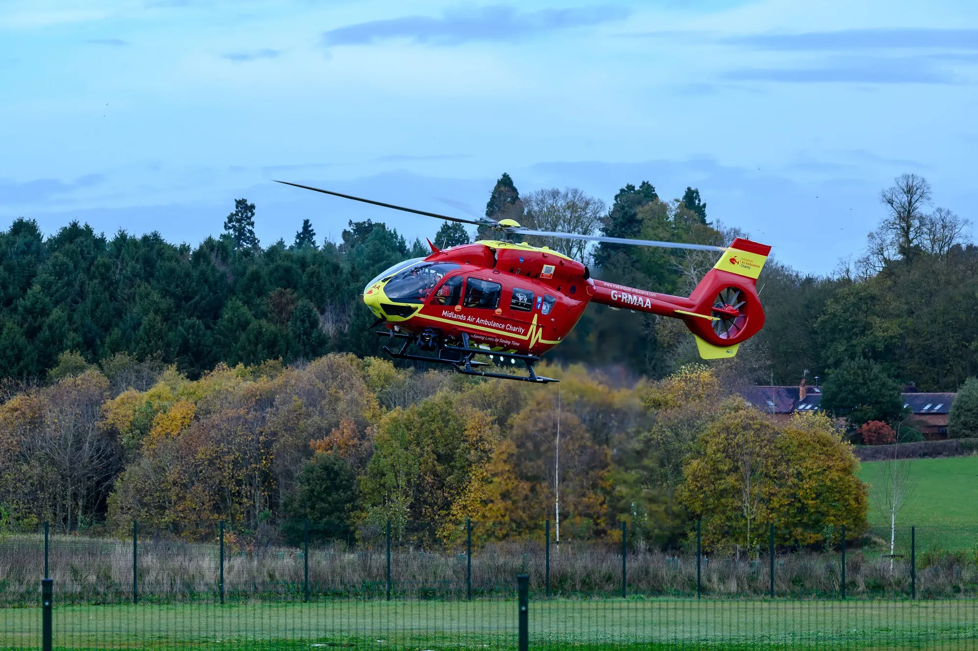 Maac Helicopter Flying Low Over A Field With Trees In The Background