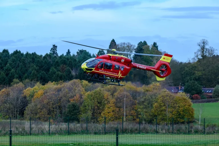 Maac Helicopter Flying Low Over A Field With Trees In The Background