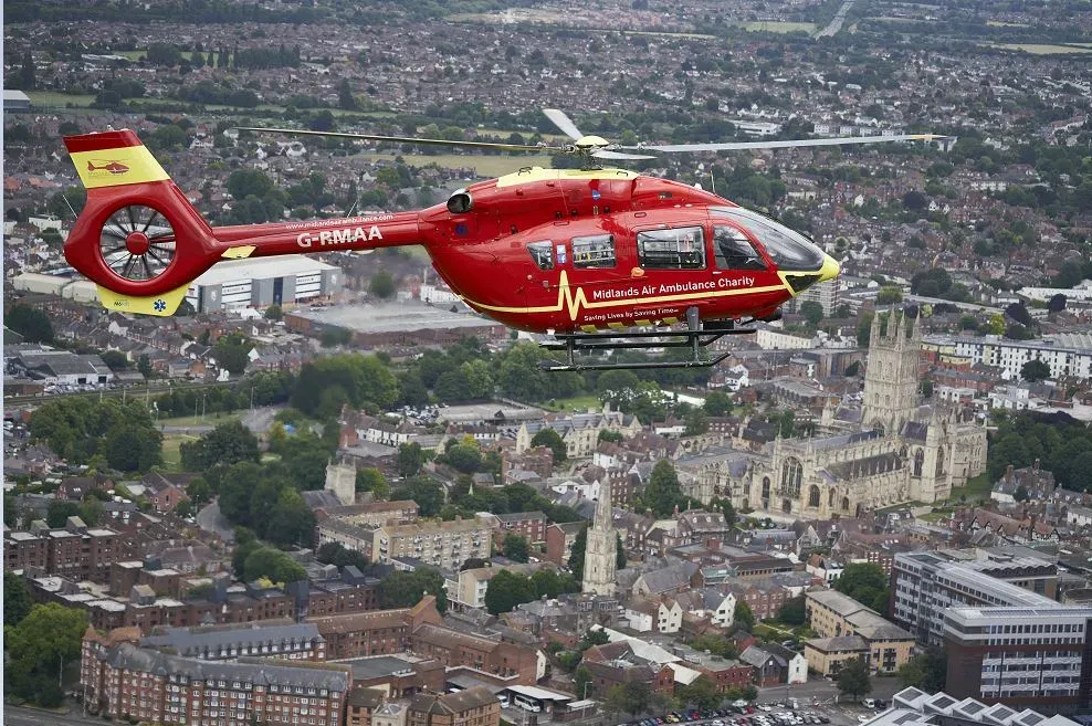 Maac Helicopter Flying Over A City With A Church In The Background