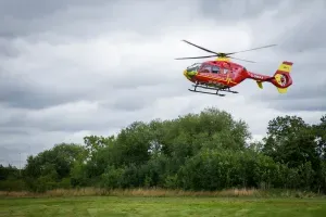 Maac Helicopter Flying Over A Field With Trees In The Background