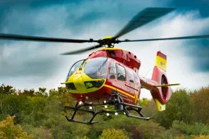 Maac Helicopter Flying Over A Forest With A Cloudy Sky