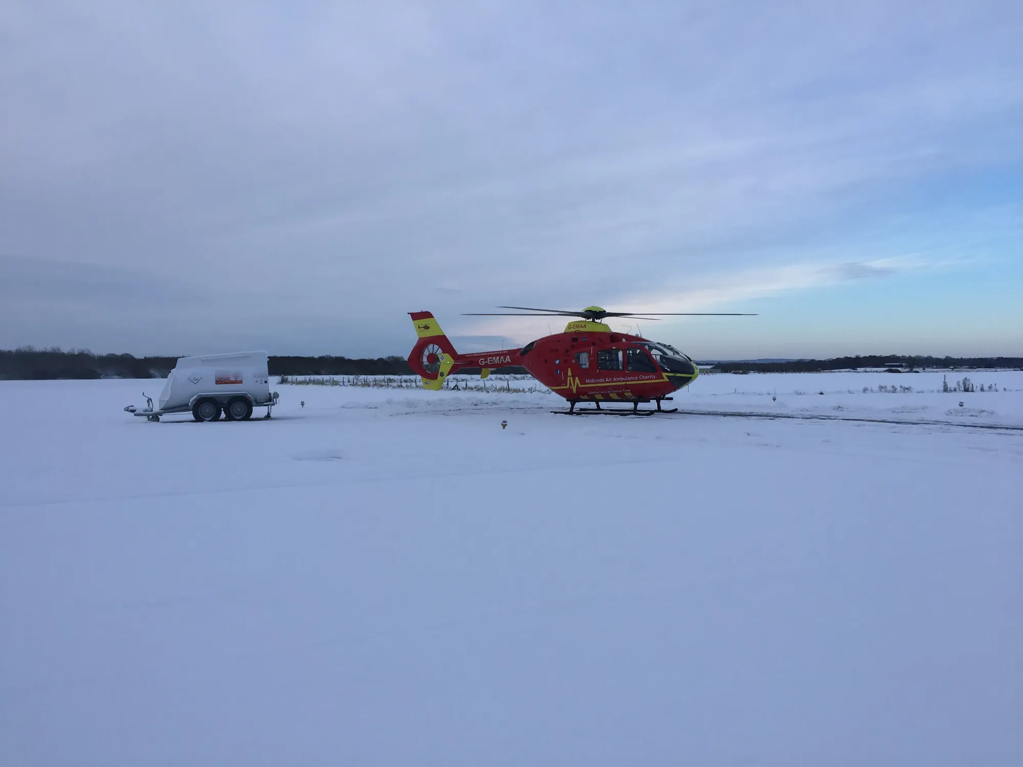 Maac Helicopter On A Snowy Field With A Truck In The Background
