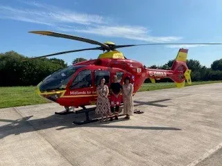 Maac Helicopter With People Standing In Front Of It On A Runway