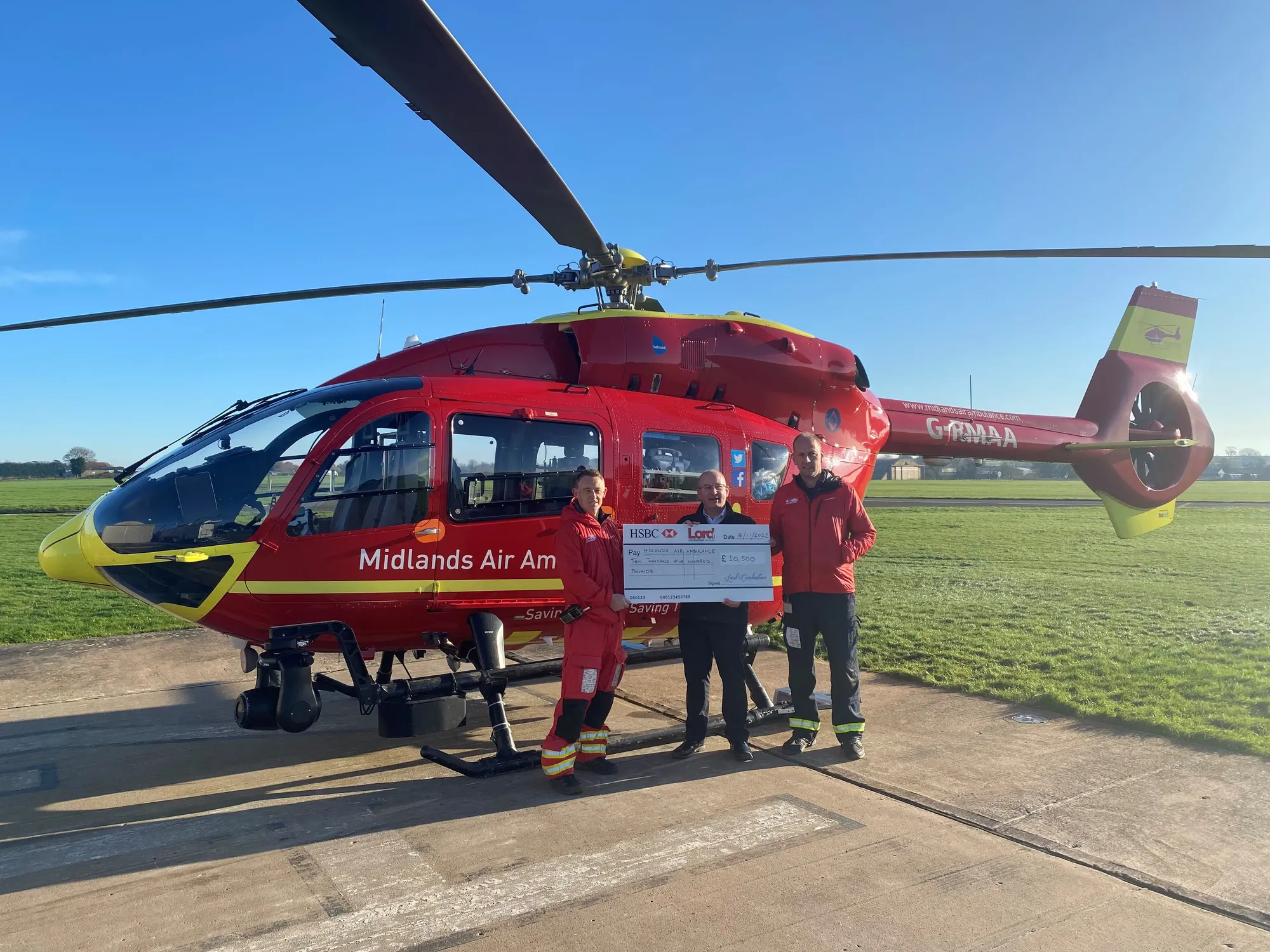 Maac Helicopter With Two People Standing Next To It On A Runway