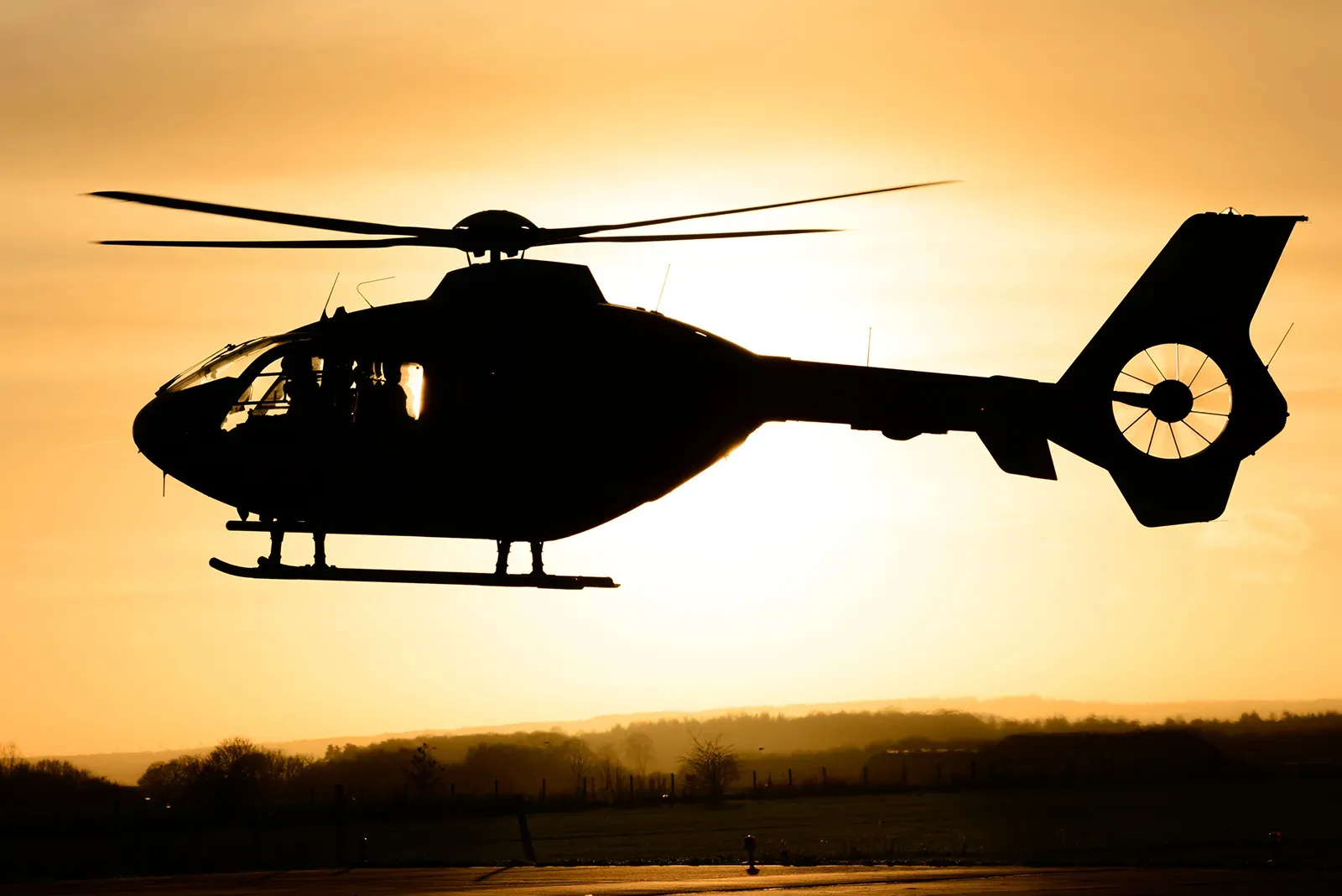Maac Maac Helicopter Flying In The Air At Sunset With A Person Standing On The Ground Helicopter Flying In The Air At Sunset With A Person Standing On The Ground