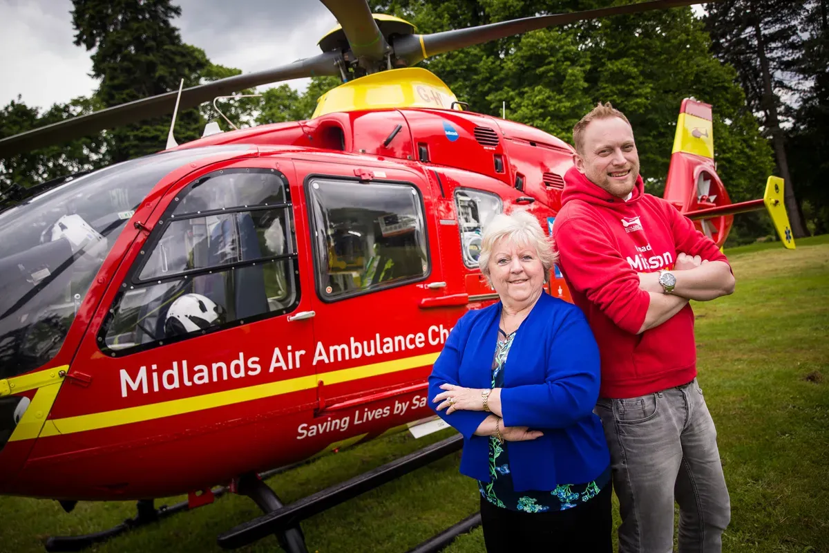 Maac Man And Woman Standing In Front Of A Helicopter