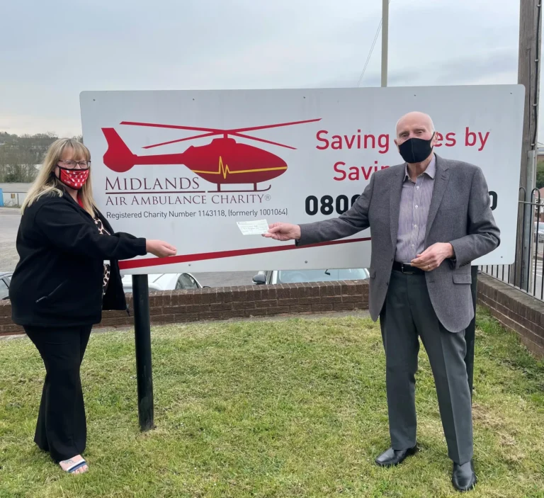 Maac Man And Woman Standing In Front Of A Sign With A Helicopter On It
