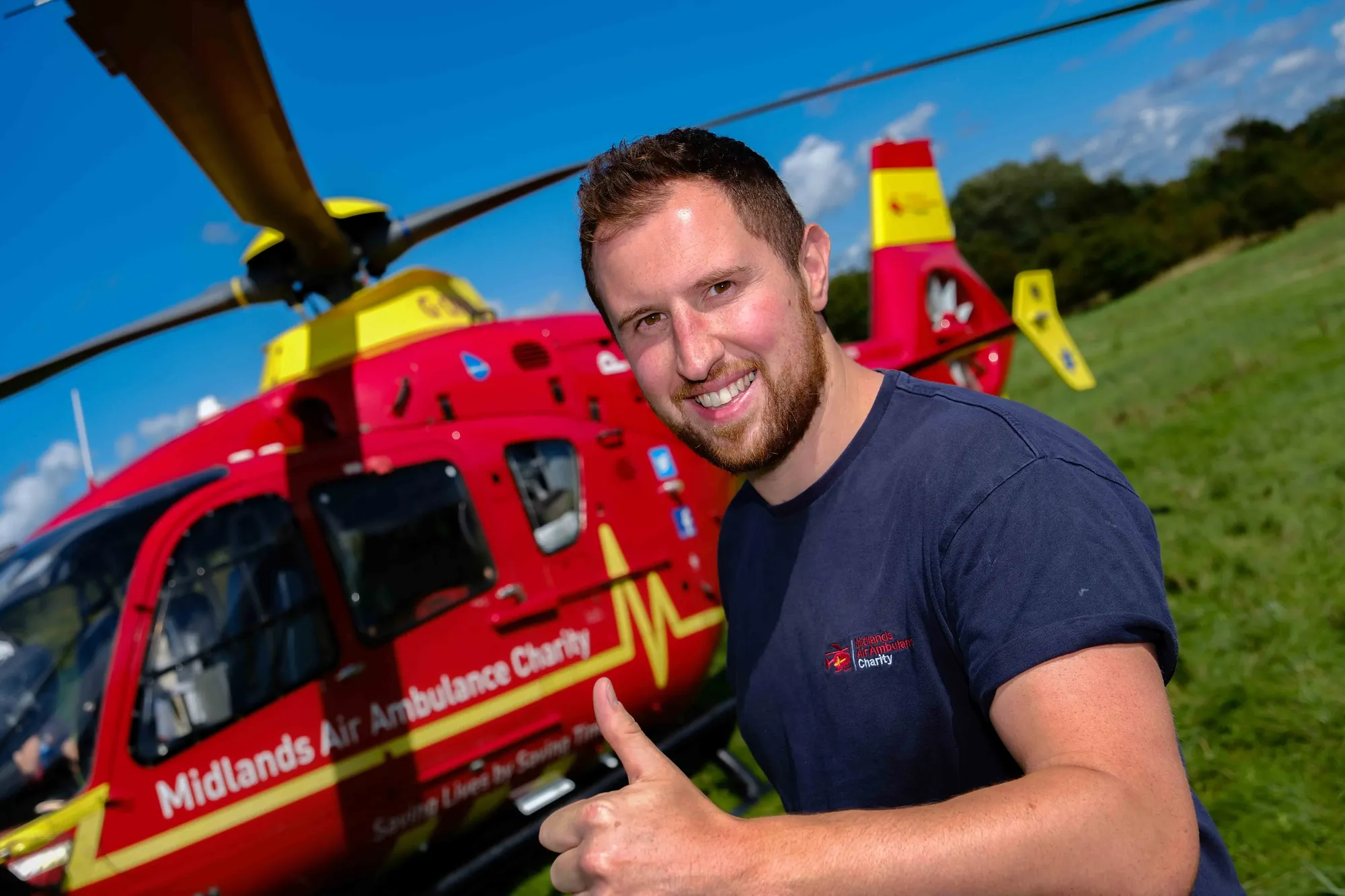 Maac Man Giving A Thumbs Up In Front Of A Helicopter