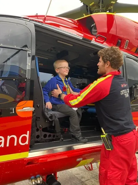 Maac Man Helping A Boy Get Out Of A Helicopter