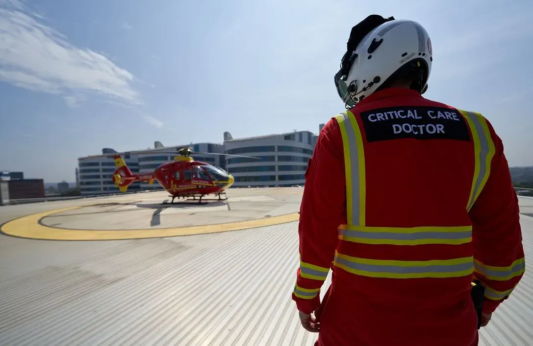 Maac Man In A Red Uniform Standing In Front Of A Helicopter