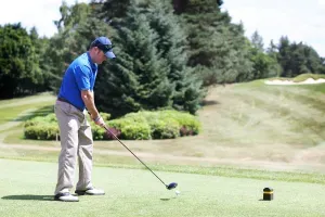 Maac Man In Blue Shirt Playing Golf On A Green Course