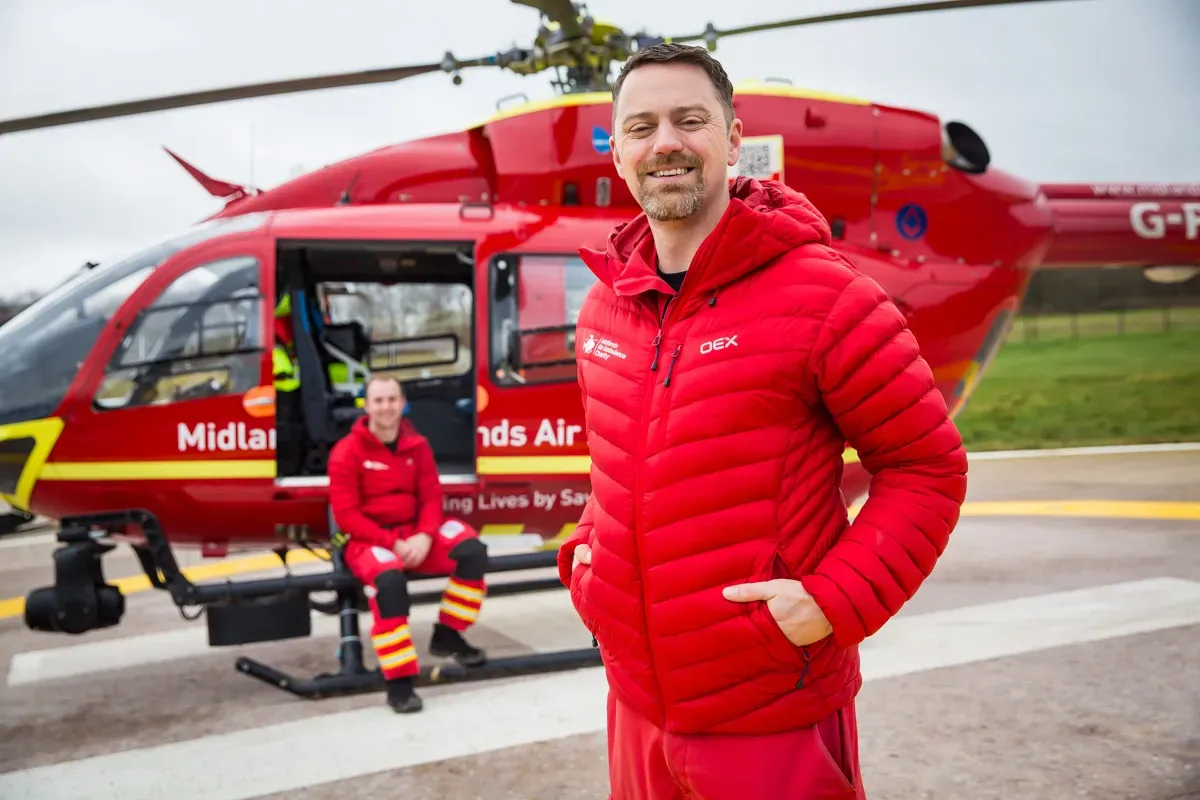 Maac Man In Red Jacket Standing In Front Of A Helicopter