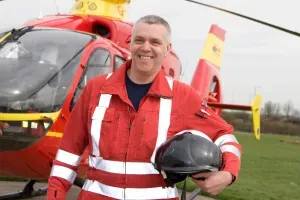Maac Man In Red Uniform Standing In Front Of A Helicopter