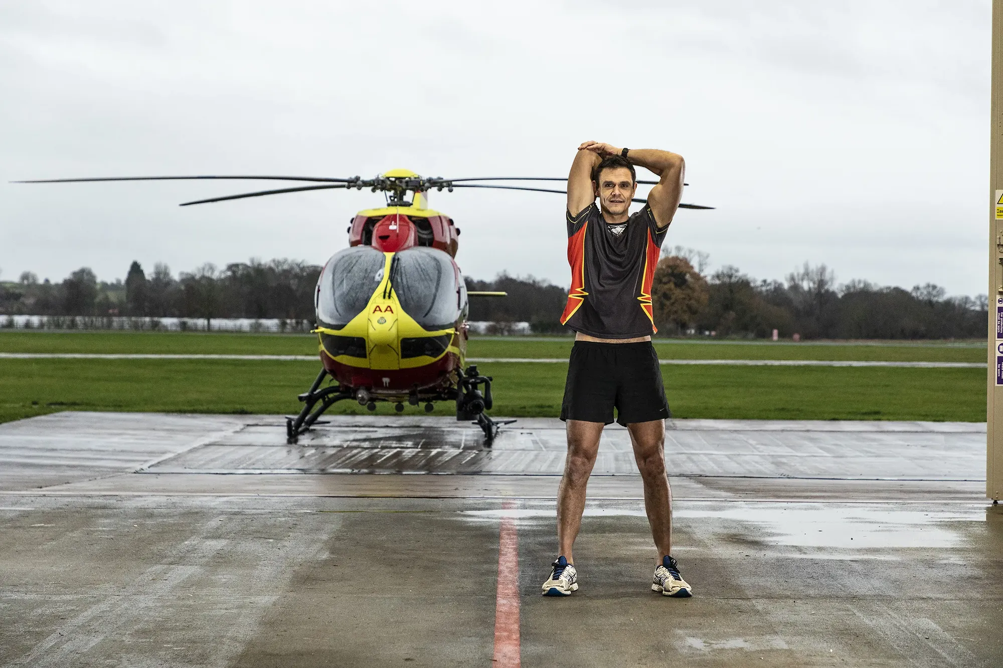 Maac Man Standing In Front Of A Helicopter On A Runway