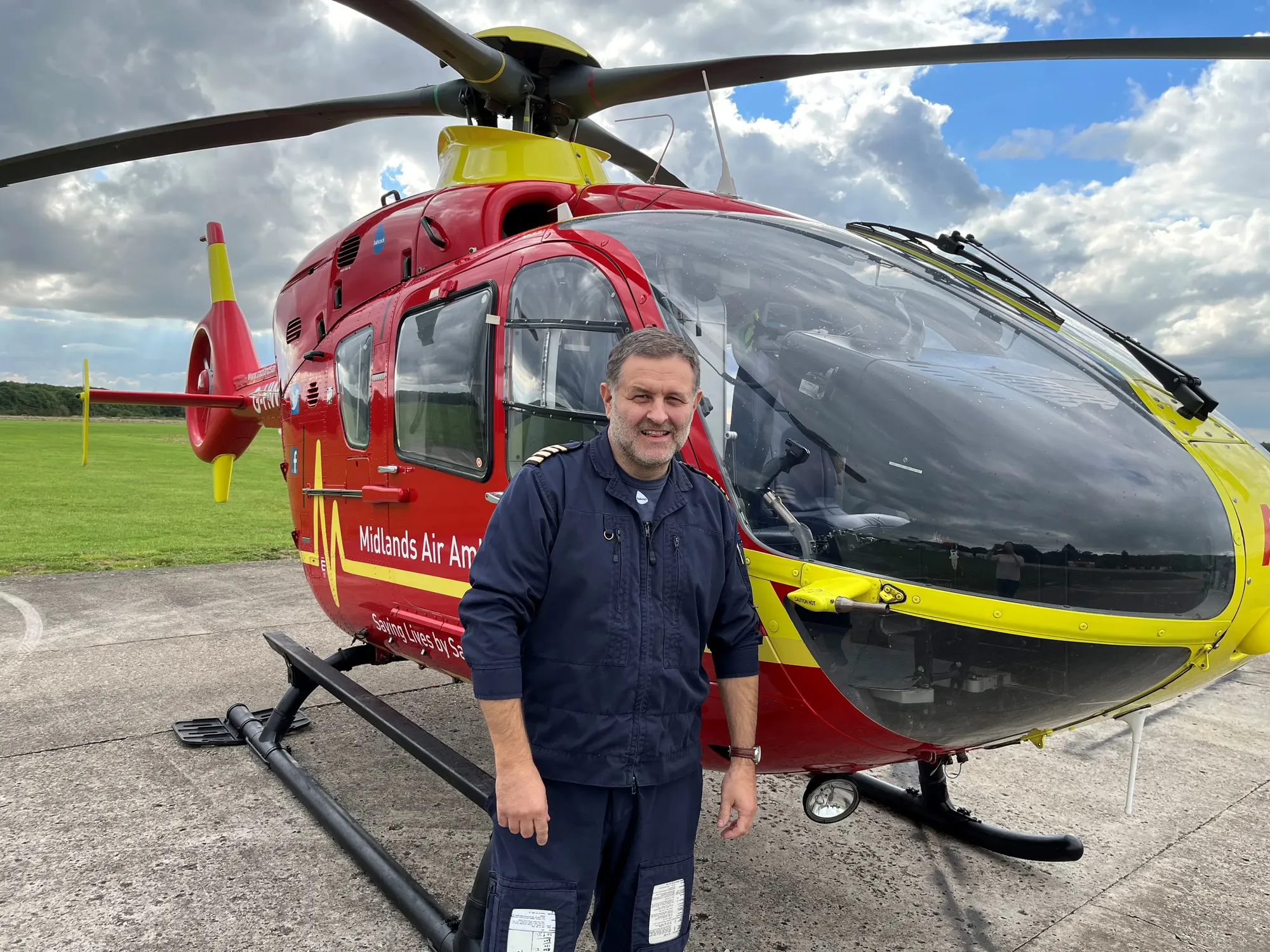 Maac Man Standing In Front Of A Helicopter On A Runway