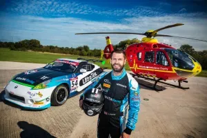 Maac Man Standing Next To A Car And A Helicopter