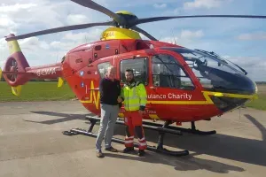 Maac Man Standing Next To A Red Helicopter On A Runway