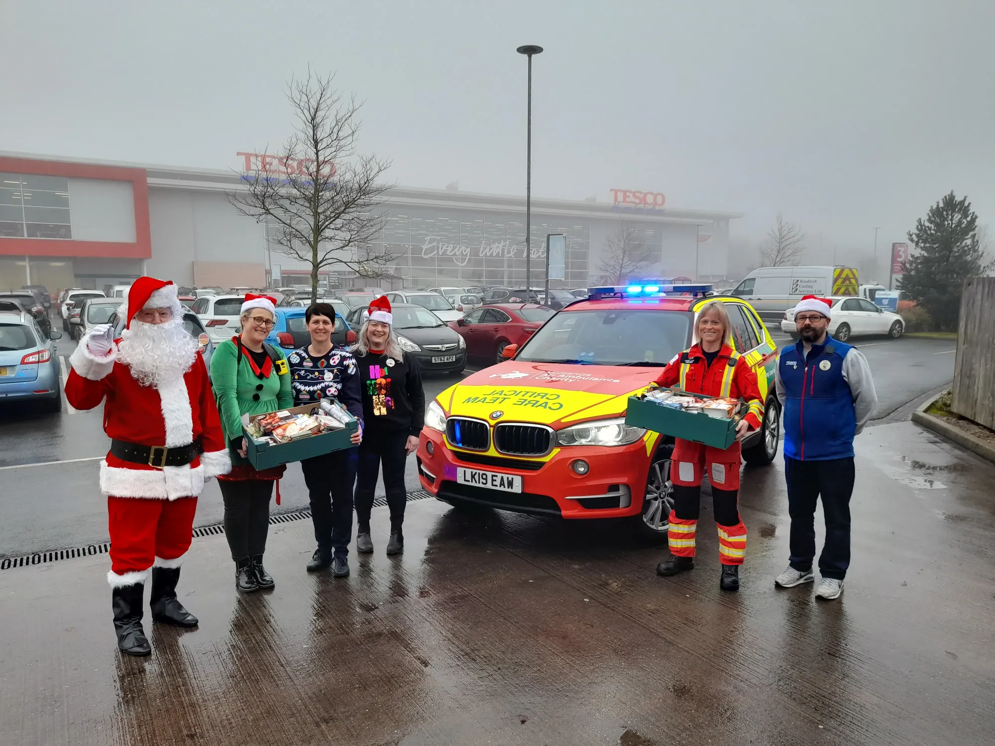 Maac People Dressed As Santa Claus And Other People Standing In Front Of A Car