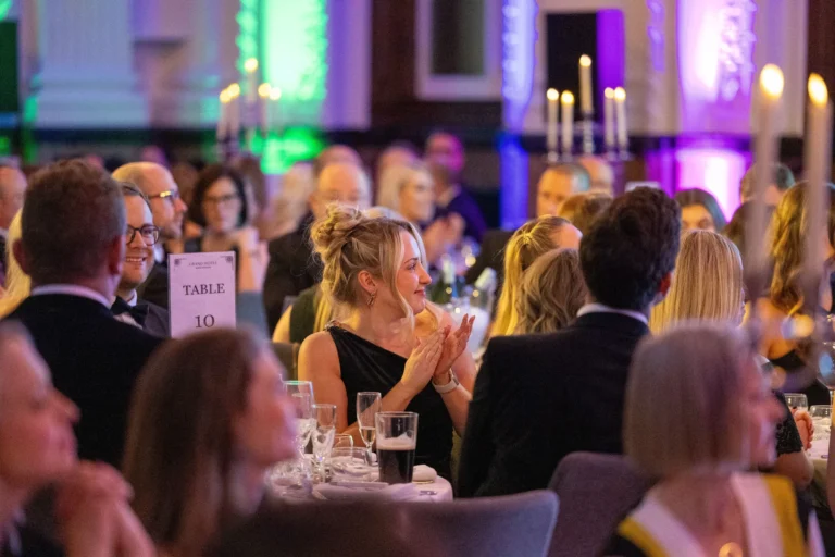 Maac People Sitting At Tables In A Banquet Hall With Candles On Them