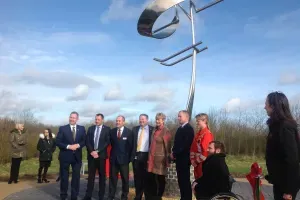Maac People Standing Around A Large Metal Pole With A Flag On It