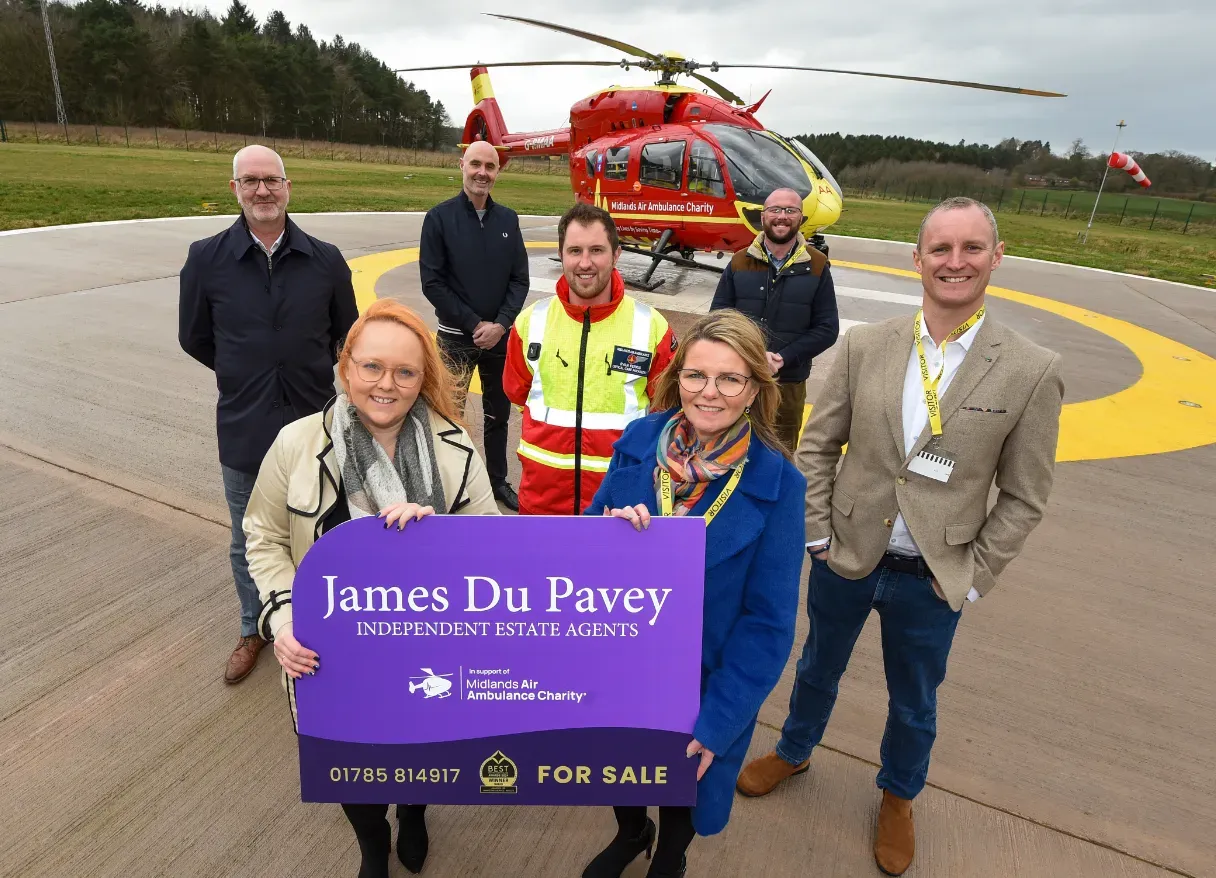 Maac People Standing In Front Of A Helicopter Holding A Sign
