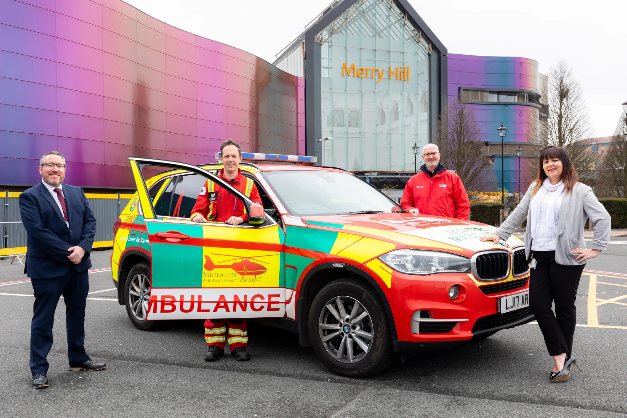 Maac People Standing Next To A Multi Colored Car In A Parking Lot