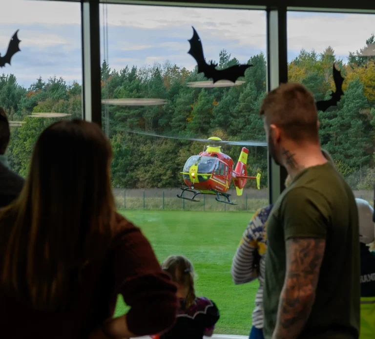 Maac People Watching A Helicopter Fly By Through A Window With Bats Flying Overhead